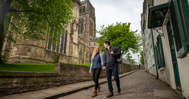 man and woman walking past Durham Cathedral